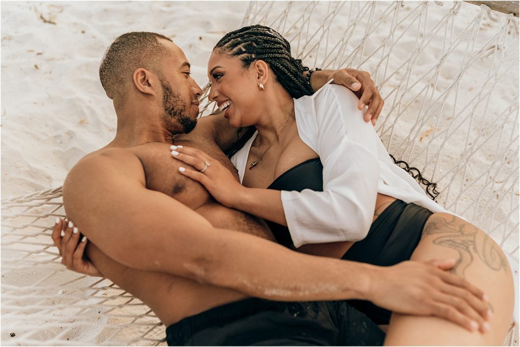 couple laughing in hammock on beach engagement session