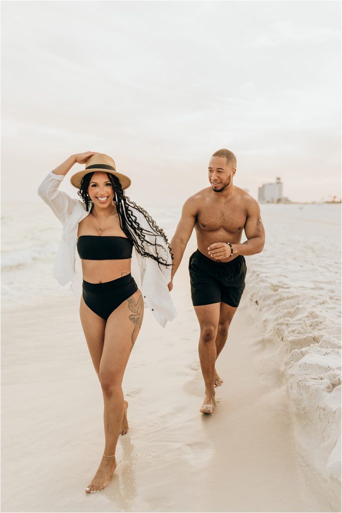 girl running ahead of boy on beach in swimwear