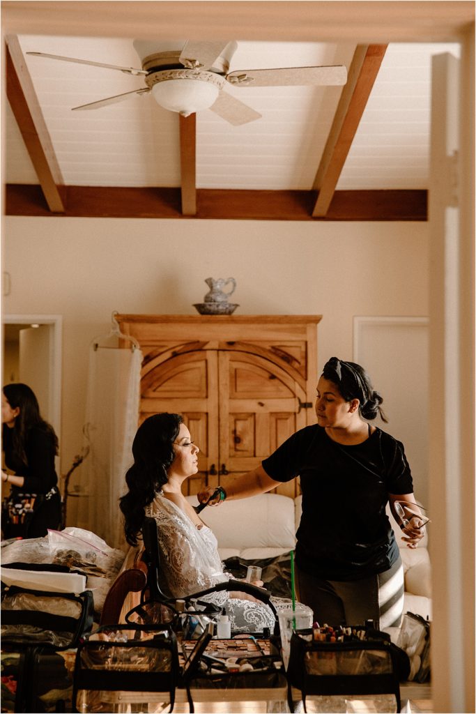 Bride getting makeup done in parent's home at backyard palm springs wedding venue