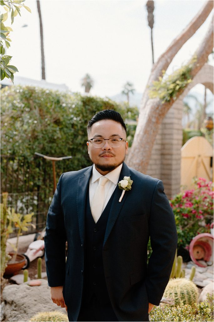 groom posing in garden at backyard palm springs wedding venue