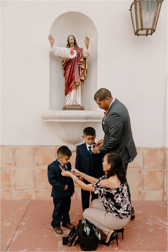 family adjusting little kid's boutonniere before wedding begins at backyard palm springs wedding venue