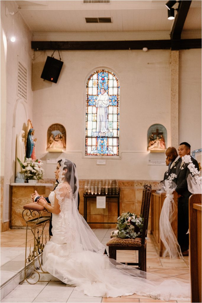 bride and groom kneeling praying inside cathedral at backyard palm springs wedding venue