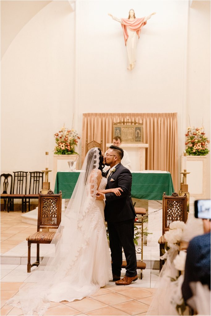 bride and groom sharing first kiss inside cathedral at backyard palm springs wedding venue