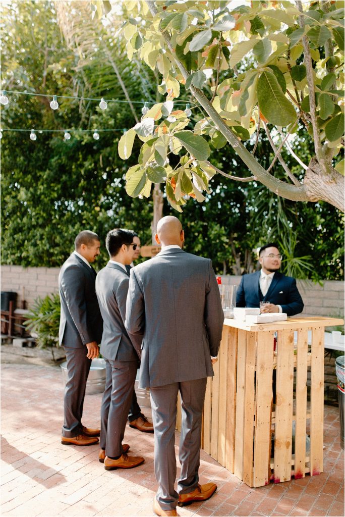 groom serving drinks behind bar he built at backyard palm springs wedding venue