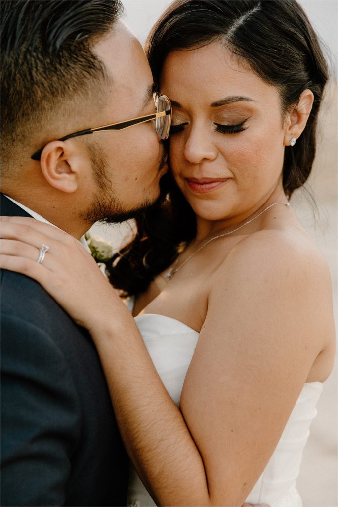groom kissing bride's cheek in palm springs desert